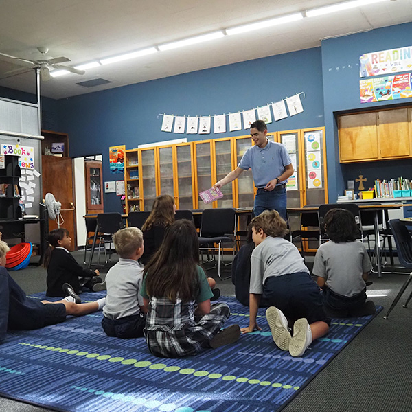 A librarian showing an illustration in a book to a group of seated students