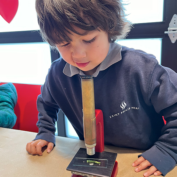 A student squinting, viewing a slide through a microscope
